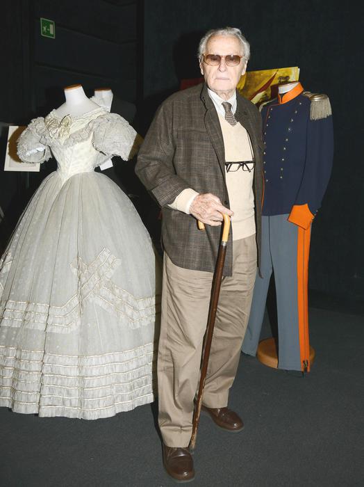 Il costumista Piero Tosi, posa vicino agli abiti di scena di Claudia Cardinale e di Alain Delon, durante la conferenza stampa per la presentazione della versione restaurata del film di Luchino Visconti 'Il Gattopardo', nella Casa del Cinema di Villa Borghese a Roma, 25 ottobre 2013. ANSA/CLAUDIO ONORATI